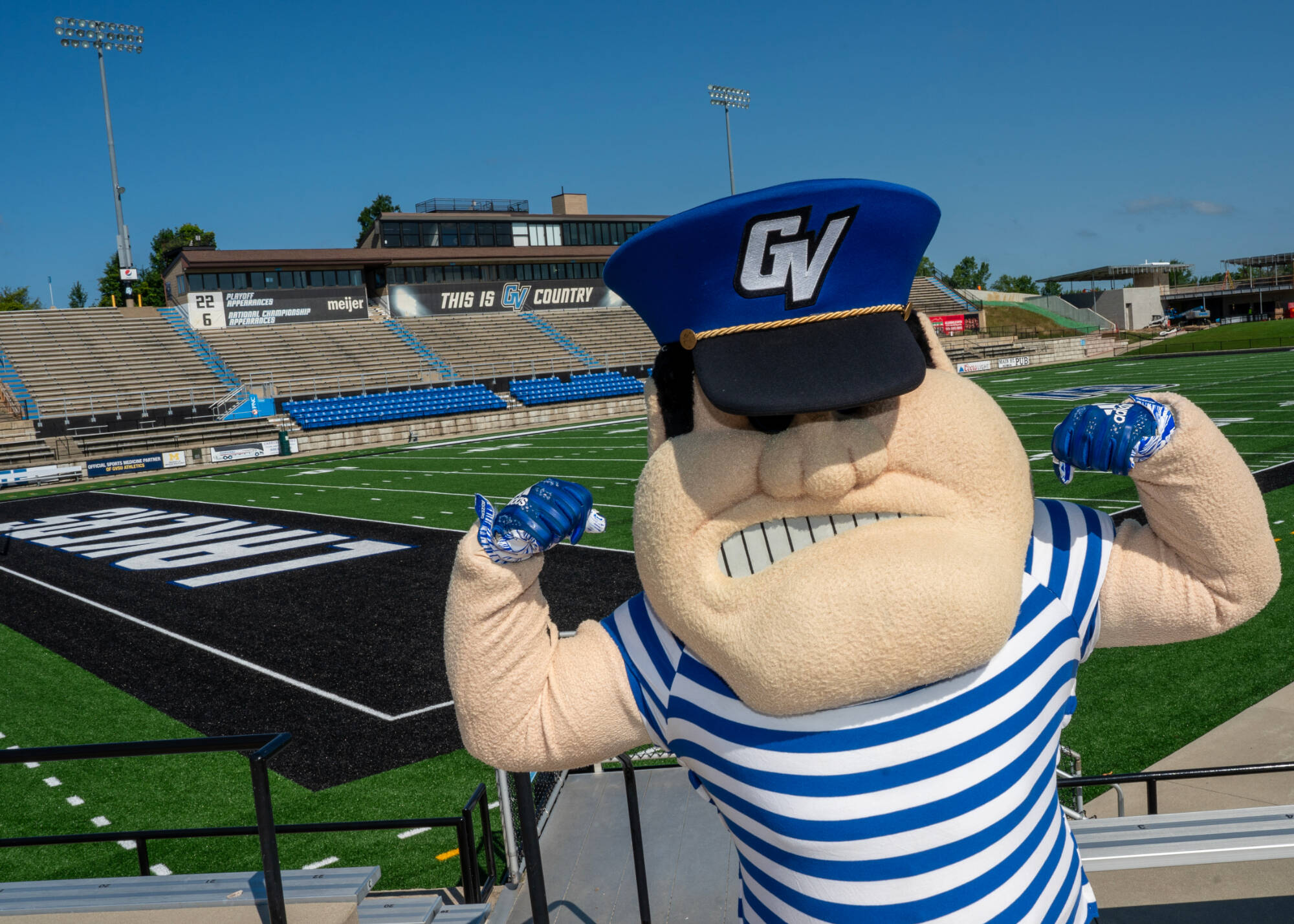 Louie The Laker showing his arm muscles on a football field